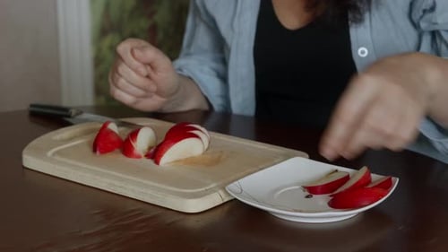 Woman Arranges Red Apple Slices on White Plate