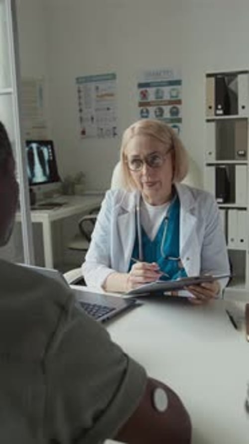 Médico generalista que toma notas en la tarjeta médica y consulta al paciente