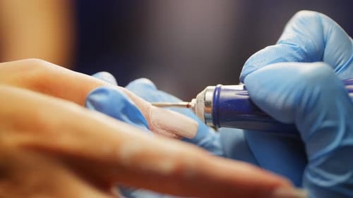 A Manicurist Files a Client's Nails with a File in a Beauty Salon