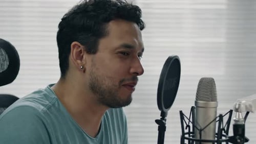 Close-up of a person speaking into a microphone while recording in a creative workspace
