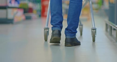 Closeup of Feet of Single Man at Shopping in Supermarket Man Walking and Rolling Cart Prores