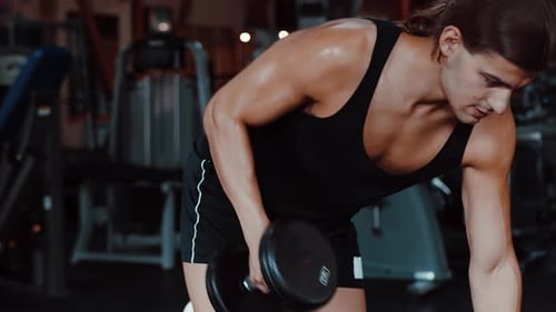 Male Athlete Workout in Gym Lifting Dumbbell with Hand Fit and Muscular Man with a Longhair Trains