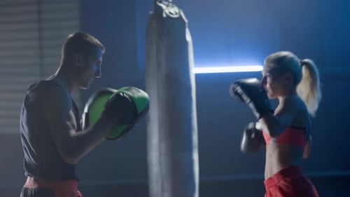 Fit Woman Kickboxing With Trainer in a Gym