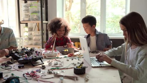 Children building robotics with laptops and tools indoors