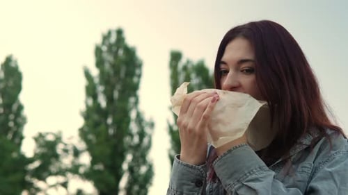 Woman Eats Sandwich Outside in the Park