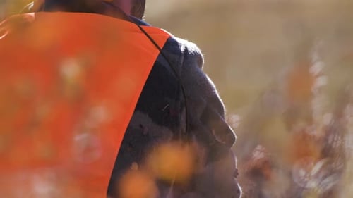 Hunter waits in the woods by his rifle. Close Up pans from face to rifle. 4K