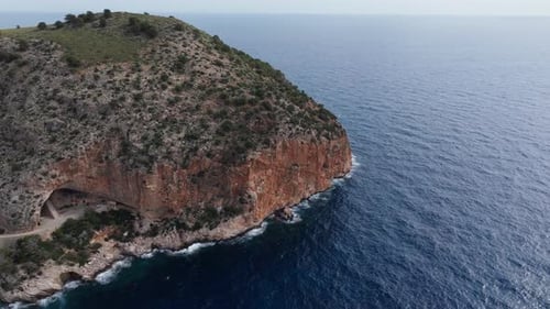 Majestic Aerial View of a Steep Cliff Plunging Into Deep Blue Mediterranean Sea Natural Cave at the