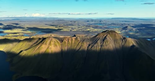 Majestic Aerial View Of Sunlit Volcanic Peaks And Vast Rugged Valleys In The Wilderness