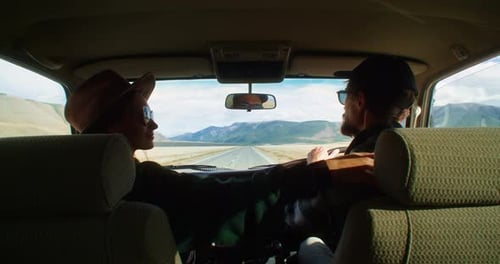 Young Couple Kissing in Car During Road Trip at Sunset