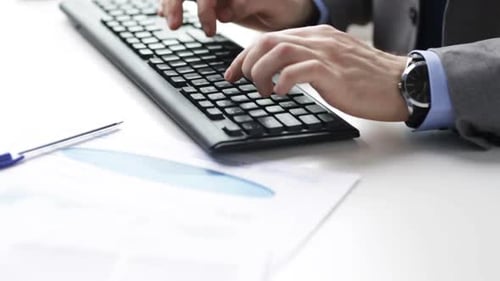 Geschäftsmann analysiert Diagramme und tippt auf der Tastatur im modernen Büro