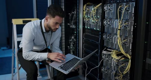 Man Working on Laptop in Server Room