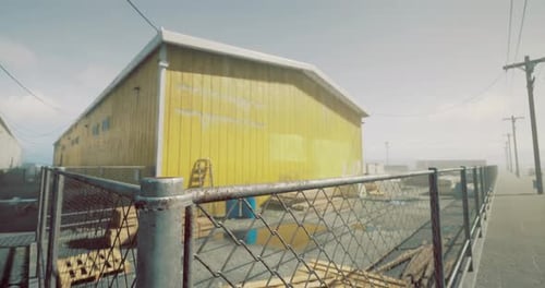 Edificio amarillo brillante rodeado de una cerca en un área industrial a la luz del día