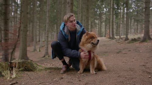A Man Kissing His Chow Chow Dog In The Woods