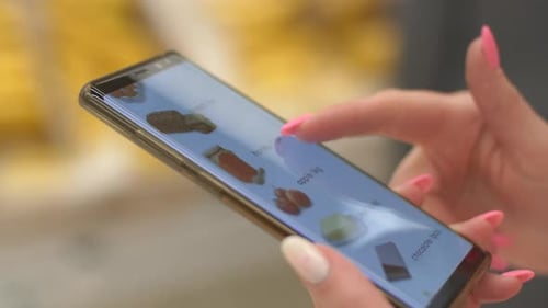 Woman customer checks shopping list on smart phone in grocery store aisle