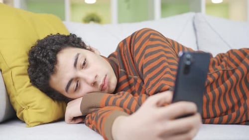 Young Man Looking at Cell Phone on Sofa