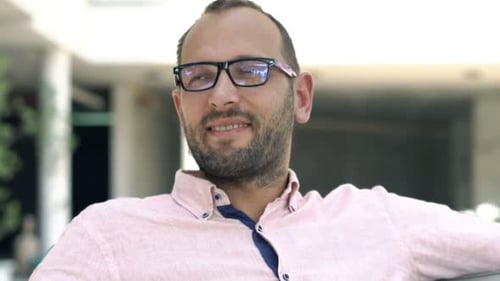 Young, Happy Man Relaxing on Sofa While Sitting in Cafe in City 30s