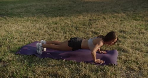 Woman Doing Pushups on Yoga Mat Outdoors
