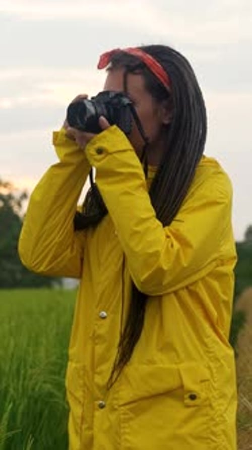Photographer Wearing Yellow Raincoat Taking Pictures in Green Field