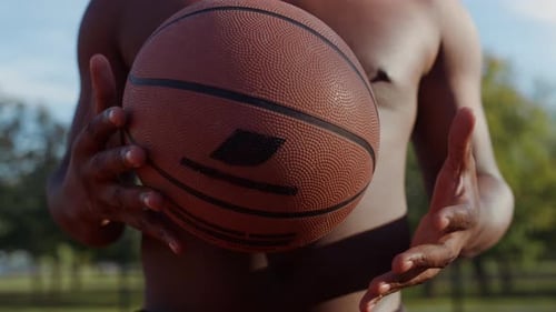 African american streetball player training hands throwing ball in slow motion