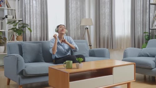 Woman Listening and Dancing to Music on Couch