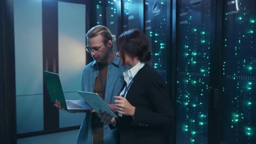 Um homem e uma mulher colaboram em uma sala de servidores de alta tecnologia analisando dados