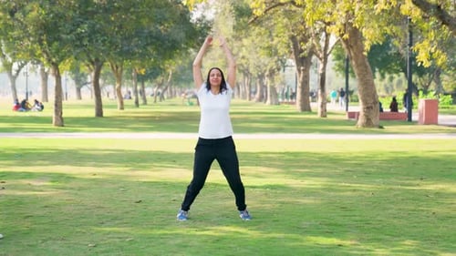 Woman Doing Jumping Jacks in Park