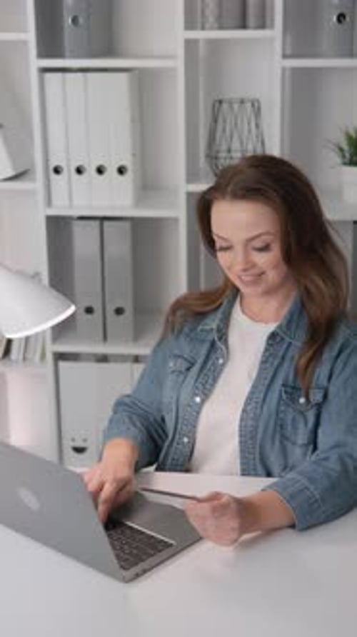 In a Modern Home Office a Woman is Dedicatedly Working on Her Laptop Ensuring an Efficient and