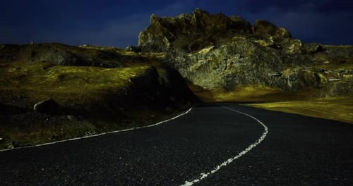 Winding Road Through Mountainous Terrain Under Night Sky with Rocky Formations