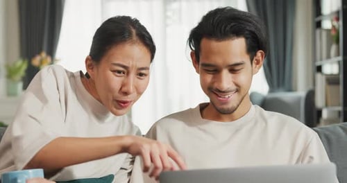Couple Laughing While Looking at Laptop Together