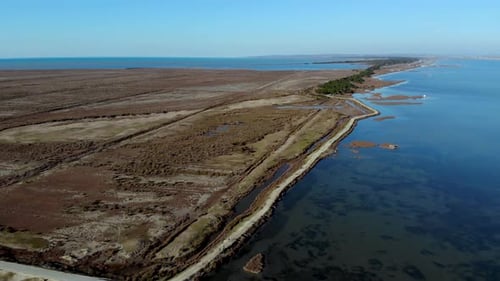 Low lying coastline of beautiful seaside with shallow lagoon and below sea level land with dry brown
