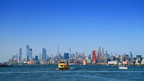 Large yellow riverboat approaches by the waterscape. Varied skyline of Manhattan
