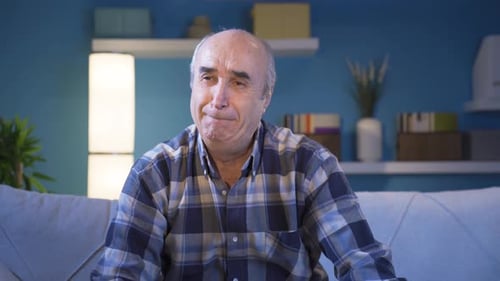 Sad old man grieving alone at home.