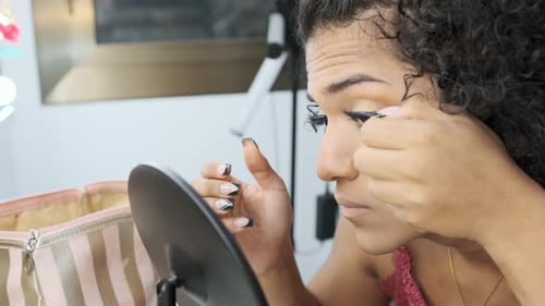 Woman Applies False Eyelashes in Home Setting