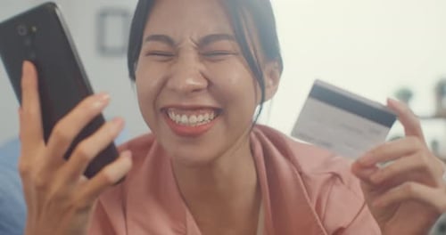 A senhora asiática usa o celular para solicitar produtos de compras on-line e pagar contas com cartão de crédito.