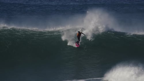 Slow motion shot of a surfer riding a wave breaking into a huge mass of white foam