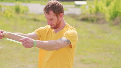 Um esportista profissional com uma camisa amarela está segurando um expansor de elástico. Ele parece focado e