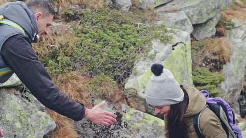 Strong Man is Helping the Girl to Climb the Hill
