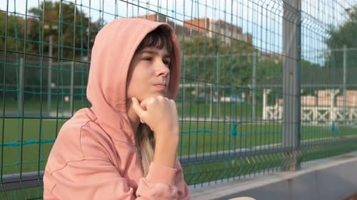 Teen Sits in Front of Fence Thinking