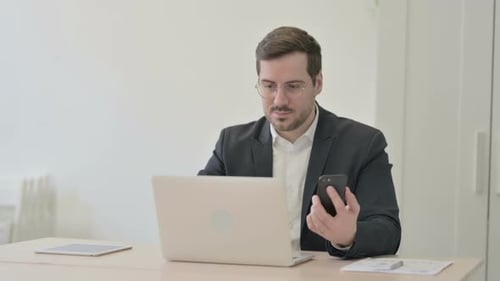 Man in Suit Working with Laptop and Phone