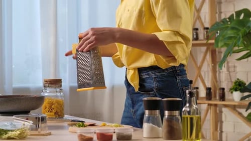 Woman Grating Cheese at Kitchen Table