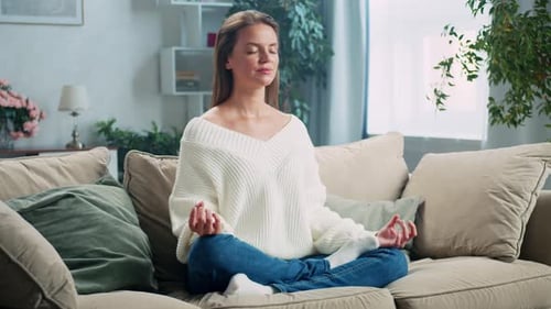 Woman Meditating on Sofa in Home Living Room