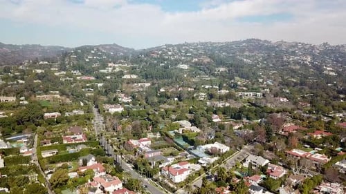 Quiet luxury neighborhood of Beverly Hills in California. Sunny day with clouds at sky. Tennis field