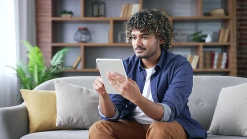 Young Adult Using Tablet on Couch at Home