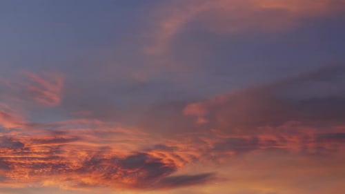 Clouds paint sky in pastel hues at evening sunset, casting tranquil shadows