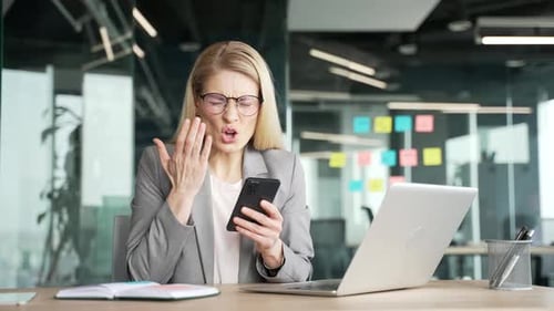 Furious Woman Looking at Smartphone in Office