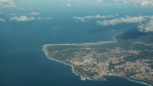 View of blue ocean water and country landscape from airplane porthole
