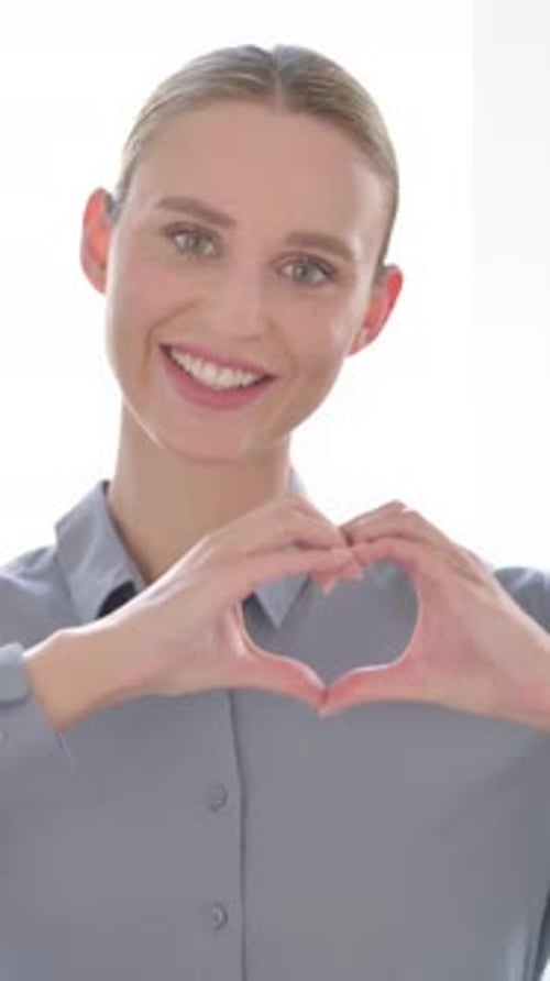 Smiling Woman Makes Heart Shape with Her Hands