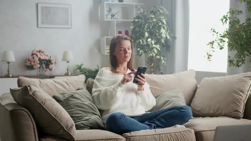 Woman Browsing Phone on Comfortable Couch Indoors