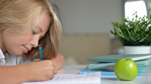 Middle School Smiling Student Boy Sitting at Desk Studying Writing Book Homework and Tablet at Class