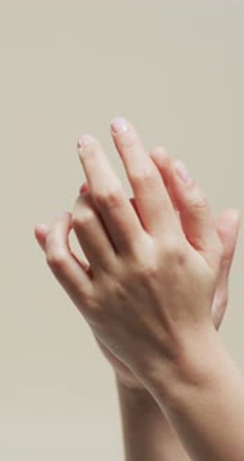 Vertical video of hands of biracial woman on beige background, slow motion